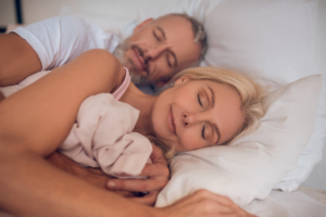 An image of a mature couple sleeping together peacefully in bed