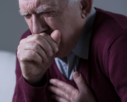 An image of a senior man with anxiety throat coughing into his hand.