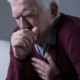 An image of a senior man with anxiety throat coughing into his hand