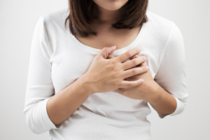 An image of a woman holding her chest due to acid reflux