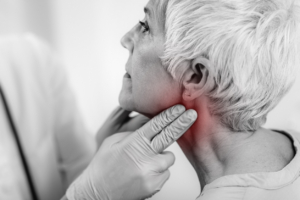 An image of a doctor feeling a woman's reddened neck for throat cancer. 