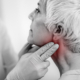 An image of a doctor feeling a womans reddened neck for throat cancer