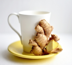 An image of ginger root on a saucer with a tea cup