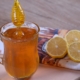 An image of a glass of honey beside several lemon slices on a table