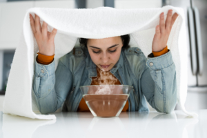An image of a woman breathing steam from a bowl of hot liquid