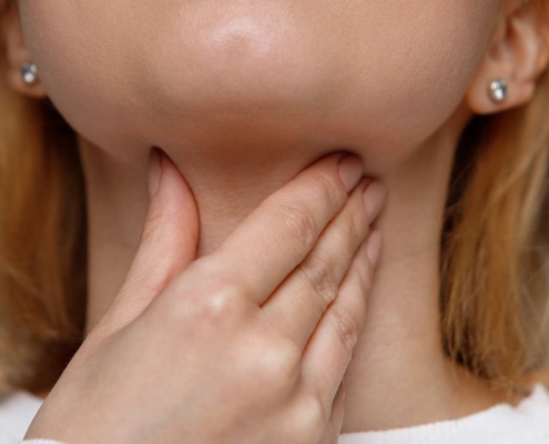 A cropped image of a woman feeling her sore throat.