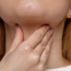 A cropped image of a woman feeling her sore throat